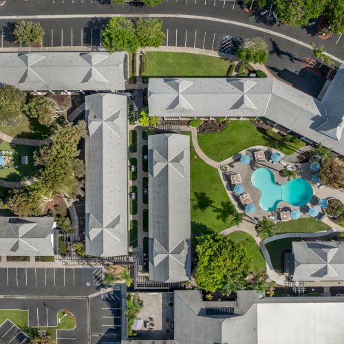 Aerial view of a modern office campus with landscaped grounds, parking lots, and a turquoise swimming pool courtyard with lounge areas.